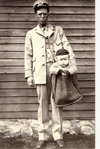 Letter carrier with a cozy looking baby (Image via National Postal Museum)